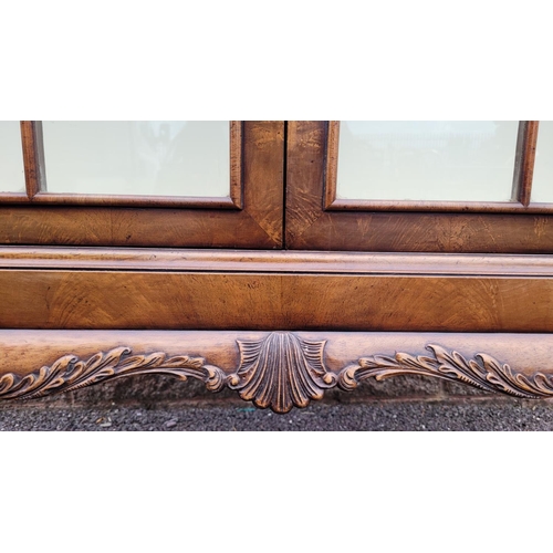 114 - A GOOD QUALITY TWO DOOR GLAZED CABINET, raised on a nice decorative scrolling carved leg, with carve... 