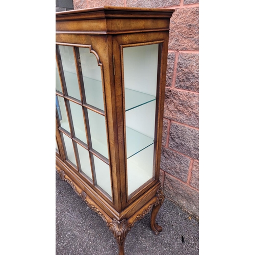 114 - A GOOD QUALITY TWO DOOR GLAZED CABINET, raised on a nice decorative scrolling carved leg, with carve... 