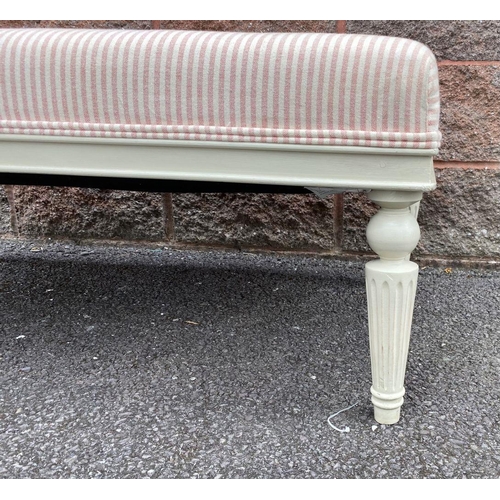 128 - AN UPHOLSTERED OTTOMAN BENCH, upholstered with pale striped fabric, standing on turned leg, painted ... 