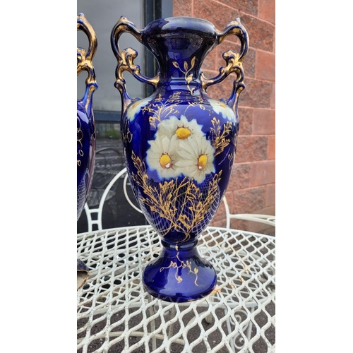 138 - A PAIR OF DECORATIVE BLUE PICTURE VASES, with floral design, some damage to the base of one as photo... 