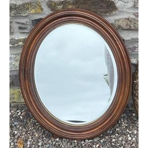 169 - A MAHOGANY OVAL WALL MIRROR, with bevelled glass, along with an oval gilt frame, with foliage and bo... 