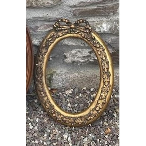 169 - A MAHOGANY OVAL WALL MIRROR, with bevelled glass, along with an oval gilt frame, with foliage and bo... 