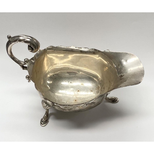 73 - A SILVER SAUCE BOAT, with shaped edge, double scroll handle, standing on three hoof feet. Maker S Bl... 