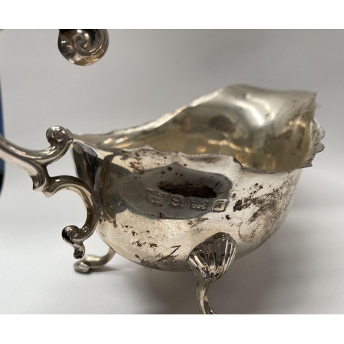 73 - A SILVER SAUCE BOAT, with shaped edge, double scroll handle, standing on three hoof feet. Maker S Bl... 