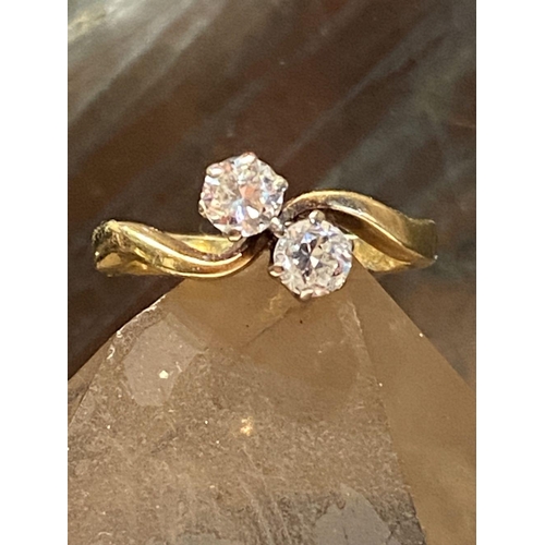 99 - A DISTINCTIVE 18CT YELLOW GOLD TWO STONE DIAMOND TWIST RING, the diamonds are claw set and weight .6... 