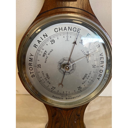 121 - AN OAK CASED ANEROID BAROMETER, British made. With carved leaf detail to the top, a silvered dial sh... 