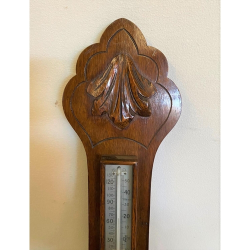 121 - AN OAK CASED ANEROID BAROMETER, British made. With carved leaf detail to the top, a silvered dial sh... 