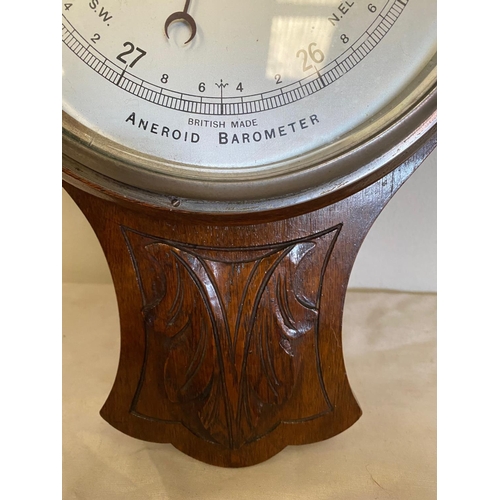 121 - AN OAK CASED ANEROID BAROMETER, British made. With carved leaf detail to the top, a silvered dial sh... 