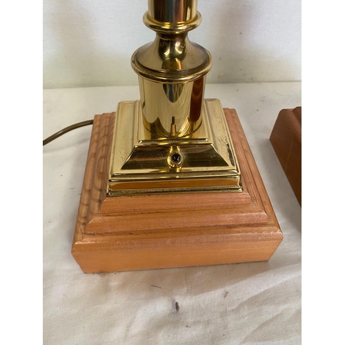 155 - A PAIR OF BRASS TABLE LAMPS IN THE STYLE OF CHANDLE STICKS, on a wooden base. 50cm tall. No shade.