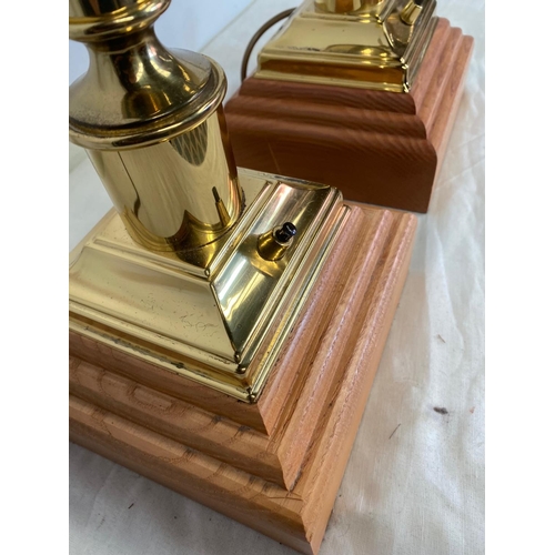 155 - A PAIR OF BRASS TABLE LAMPS IN THE STYLE OF CHANDLE STICKS, on a wooden base. 50cm tall. No shade.