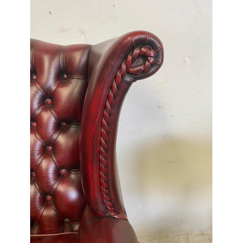 18 - A VERY GOOD QUALITY CHESTERFIELD STYLE BUTTONED WING BACK ARM CHAIR, the Ox-Blood coloured chair wit... 