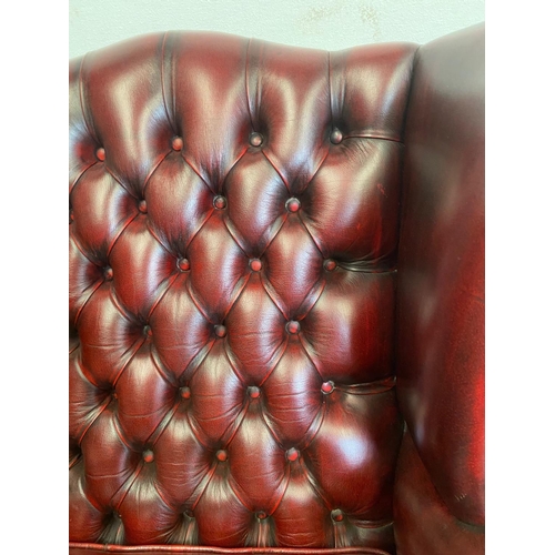 18 - A VERY GOOD QUALITY CHESTERFIELD STYLE BUTTONED WING BACK ARM CHAIR, the Ox-Blood coloured chair wit... 