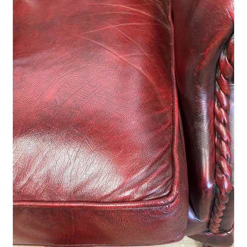 18 - A VERY GOOD QUALITY CHESTERFIELD STYLE BUTTONED WING BACK ARM CHAIR, the Ox-Blood coloured chair wit... 