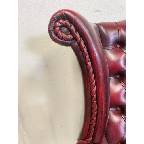 18 - A VERY GOOD QUALITY CHESTERFIELD STYLE BUTTONED WING BACK ARM CHAIR, the Ox-Blood coloured chair wit... 