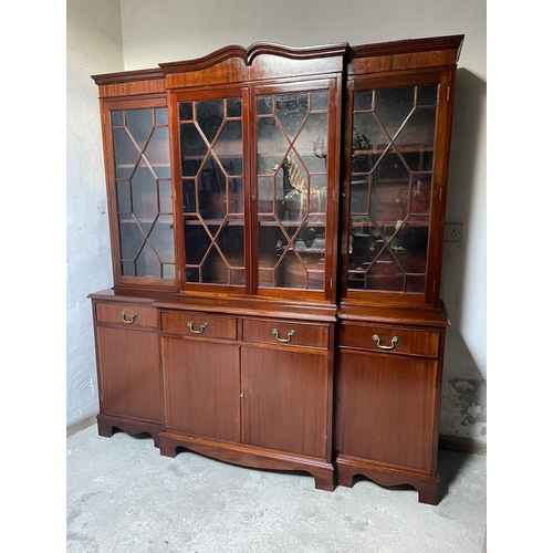 46 - A GOOD QUALITY IRISH MAHOGANY BREAK-FRONT LIBRARY BOOKCASE, the pediment with curved detail to the c... 