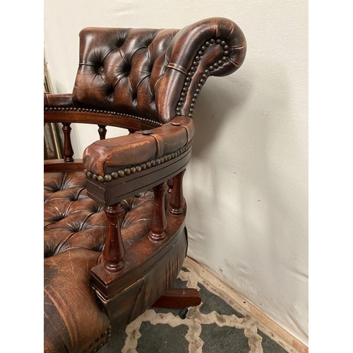 12 - A BROWN LEATHER DESK/CAPTAINS CHAIR, with button back, turned spindle supports to back, standing on ... 