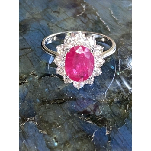 144 - A STRIKING 18CT WHITE GOLD BURMESE RUBY AND DIAMOND CLUSTER RING, the oval shaped Ruby weighs 2.70ct... 