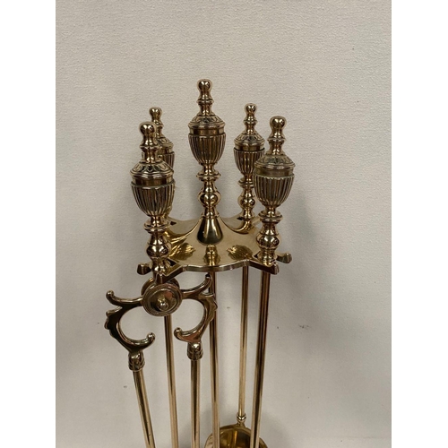 47 - AN EXCELLENT SET OF FOUR BRASS FIRE IRONS, all with finials to top, on circular platform stand. Dime... 