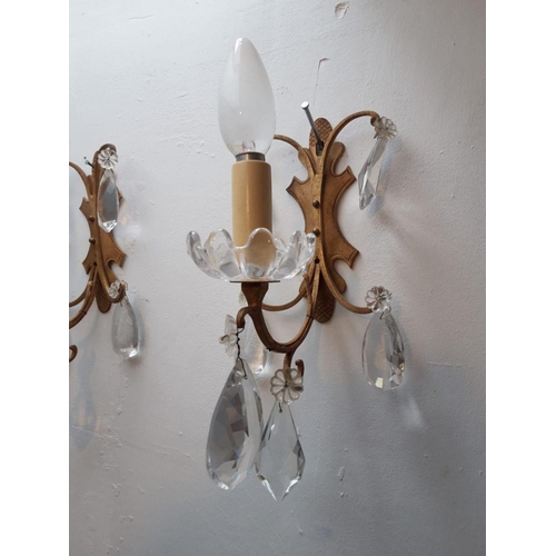 49 - A STUNNING PAIR OF EARLY 20TH CENTURY GILT BRASS TWIN WALL LIGHTS, with hanging crystal pendants. Di... 