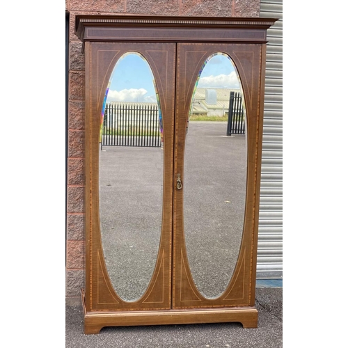 60 - AN ANTIQUE MAHOGANY TWO DOOR WARBDROBE, with dentil cornice above two doors, oval bevelled glass mir... 