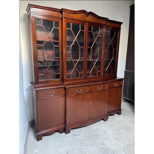 99 - A GOOD QUALITY IRISH MAHOGANY BREAK-FRONT LIBRARY BOOKCASE, the pediment with curved detail to the c... 