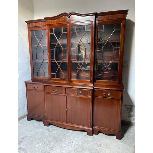 99 - A GOOD QUALITY IRISH MAHOGANY BREAK-FRONT LIBRARY BOOKCASE, the pediment with curved detail to the c... 