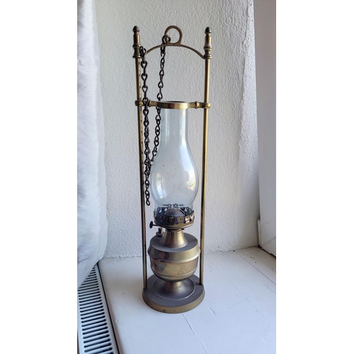 125 - A BRASS OIL LAMP WITH CLEAR GLASS CHIMNEY and brass safety frame, 51cm x 13cm (H x W)