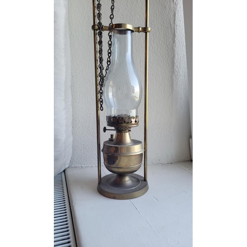 125 - A BRASS OIL LAMP WITH CLEAR GLASS CHIMNEY and brass safety frame, 51cm x 13cm (H x W)