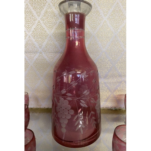 131 - A VINTAGE CRANBERRY ETCHED GLASS DECANTER ALONG WITH SIX CLEAR FOOTED GLASSES, grape floral design e... 