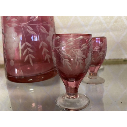 131 - A VINTAGE CRANBERRY ETCHED GLASS DECANTER ALONG WITH SIX CLEAR FOOTED GLASSES, grape floral design e... 