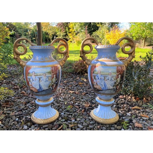 15 - A PAIR OF FRENCH STYLE SERVES PORCLEAIN TWO HANDLED URN VASES, with painted panels to front and reve... 