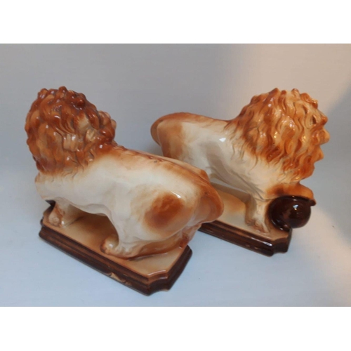 208 - A PAIR OF VINTAGE STAFFORDSHIRE PORCELAIN LION FIGURINES, in the form of maned lions with paw restin... 