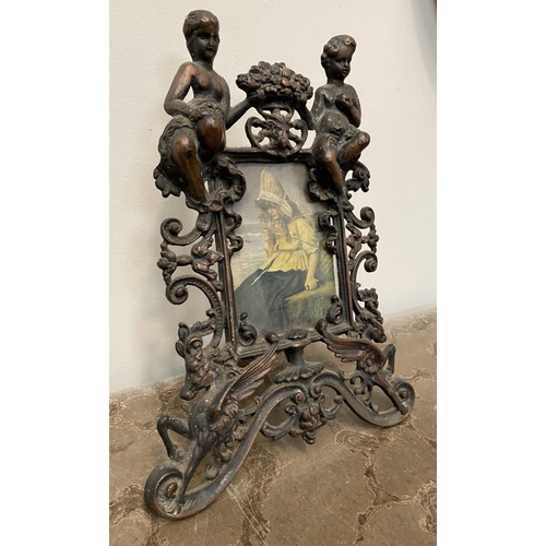 22 - A VICTORIAN CAST METAL PICTURE FRAME, featuring ornate design with two figures to top with floral cr... 