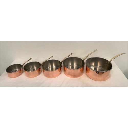 254 - A SET OF FIVE COPPER SAUCEPANS, with brass handles, in good condition.