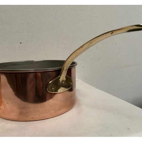 254 - A SET OF FIVE COPPER SAUCEPANS, with brass handles, in good condition.