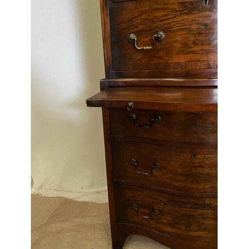 260 - A WALNUT SERPENTINE CHEST ON CHEST, with shaped cornice, four above three drawers with brass handles... 