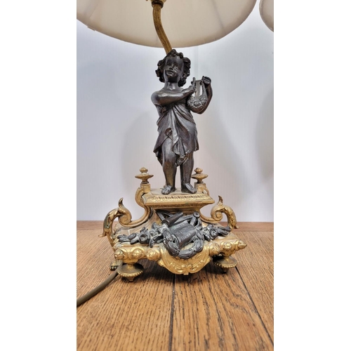 288 - A PAIR OF HEAVY PATINATED BRONZE & GILT CAST TABLE LAMPS, each with a small figure, one holding a mu... 