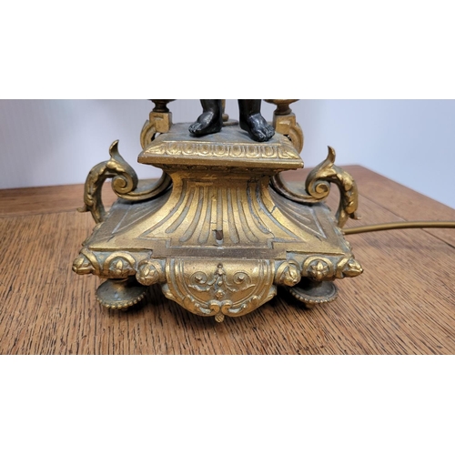 288 - A PAIR OF HEAVY PATINATED BRONZE & GILT CAST TABLE LAMPS, each with a small figure, one holding a mu... 