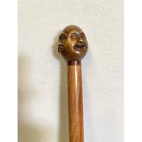 303 - AN ANTIQUE WALKING STICK WITH CARVING TO HANDLE, intricate carving of multiple faces to top, brass b... 