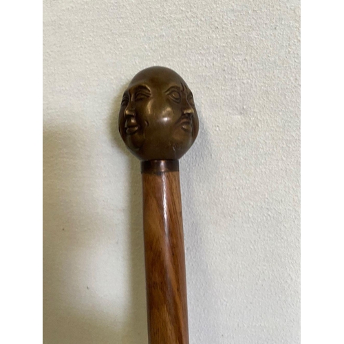 303 - AN ANTIQUE WALKING STICK WITH CARVING TO HANDLE, intricate carving of multiple faces to top, brass b... 