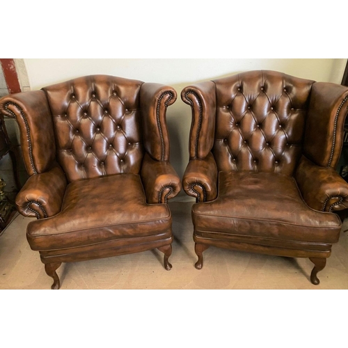 31 - A PAIR OF TAN LEATHER CHESTERFIELD WINGBACK ARMCHAIRS, stud upholstered with button back, scrolling ... 