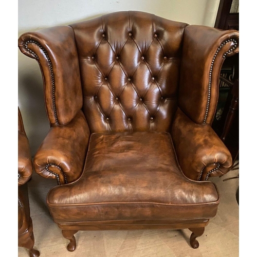 31 - A PAIR OF TAN LEATHER CHESTERFIELD WINGBACK ARMCHAIRS, stud upholstered with button back, scrolling ... 