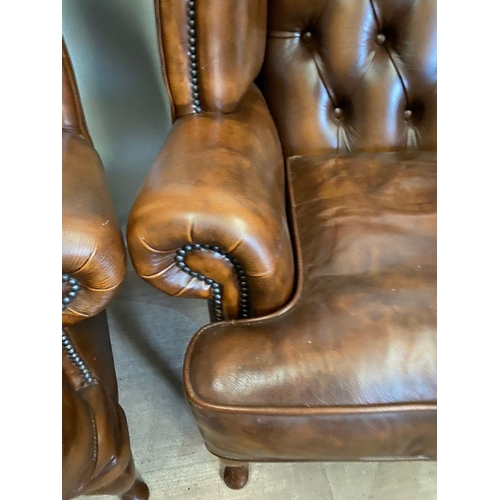 31 - A PAIR OF TAN LEATHER CHESTERFIELD WINGBACK ARMCHAIRS, stud upholstered with button back, scrolling ... 