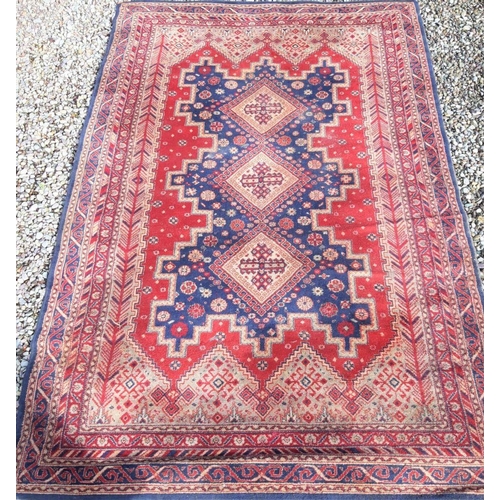 318 - A LARGE MID CENTURY MIDDLE EASTERN WOOL RUG, hand-made with triple diamond motif to centre surrounde... 