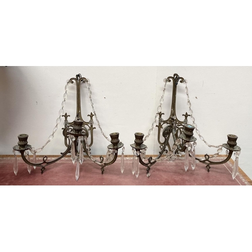 46 - A PAIR OF ANTIQUE BRONZE CRYSTAL WALL SCONCES, with three branches, shaped frame and hanging prisms.... 