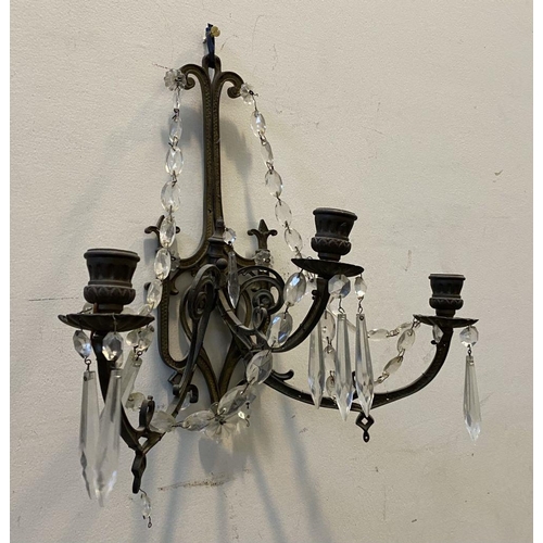 46 - A PAIR OF ANTIQUE BRONZE CRYSTAL WALL SCONCES, with three branches, shaped frame and hanging prisms.... 