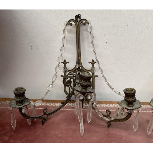 46 - A PAIR OF ANTIQUE BRONZE CRYSTAL WALL SCONCES, with three branches, shaped frame and hanging prisms.... 