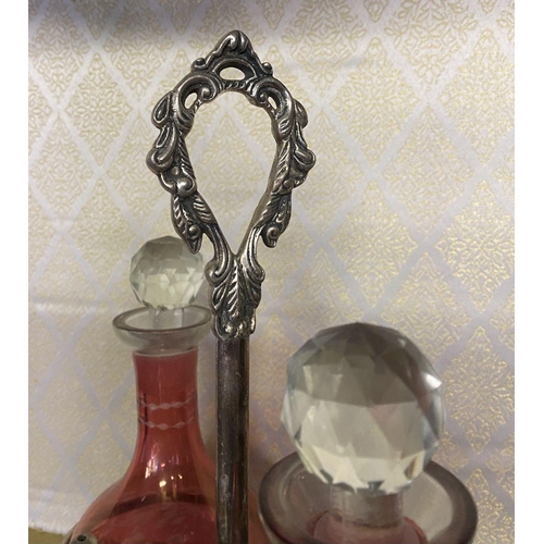 65 - AN ANTIQUE CRANBERRY GLASS CRUET SET, with two etched cranberry glass decanters with globe stoppers,... 