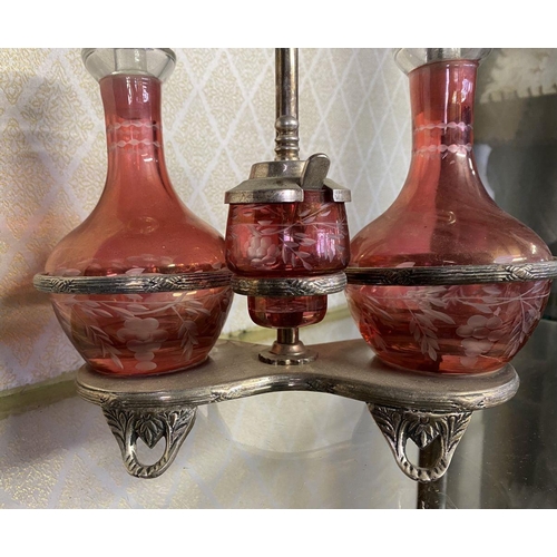 65 - AN ANTIQUE CRANBERRY GLASS CRUET SET, with two etched cranberry glass decanters with globe stoppers,... 