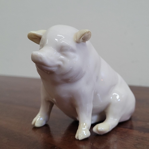 26 - A DELICATE IRISH BELLEEK PIG FIGURINE, with yellow lustre highlights, the seated pig is in excellent... 